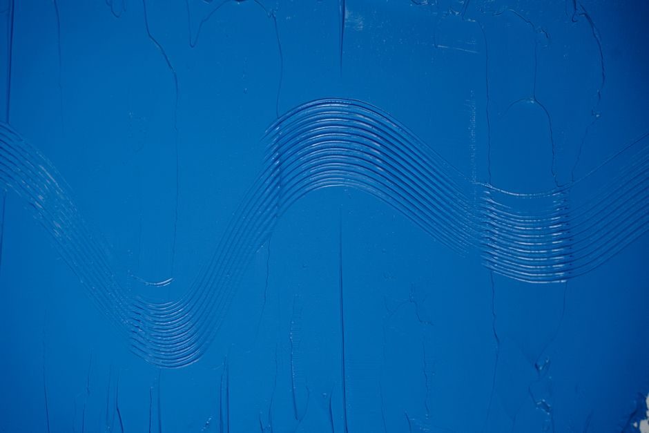 群青 — Close-up of a wavy textured pattern on blue painted canvas, providing artistic background.