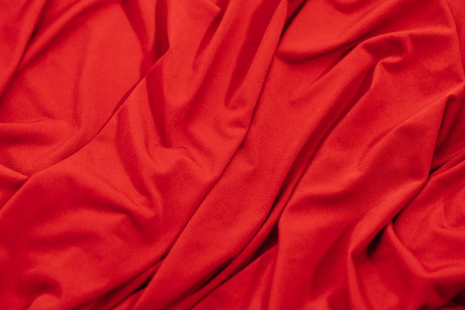 石榴裙 — Close-up of smooth red fabric with elegant drapes and folds, showcasing its vibrant texture.