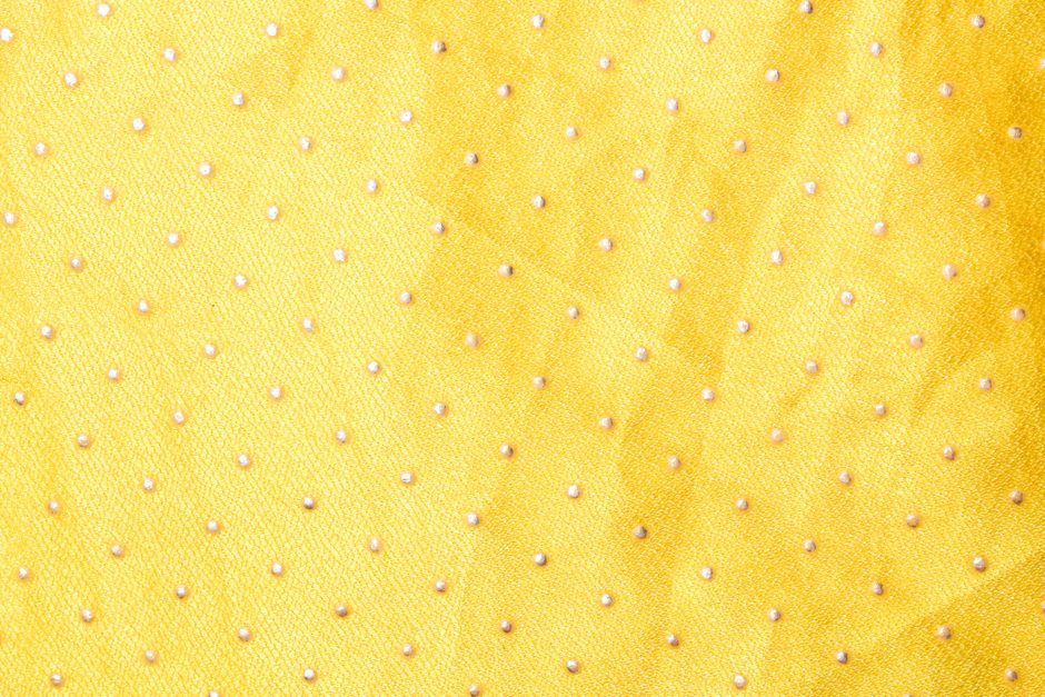 松花 — Close-up of bright yellow fabric featuring small white dots and a soft texture.