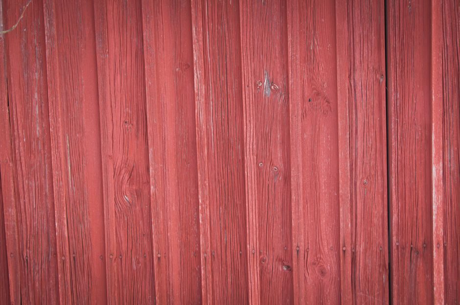 鞓红 — Detailed view of a rustic red painted wooden wall showing natural grain and texture.