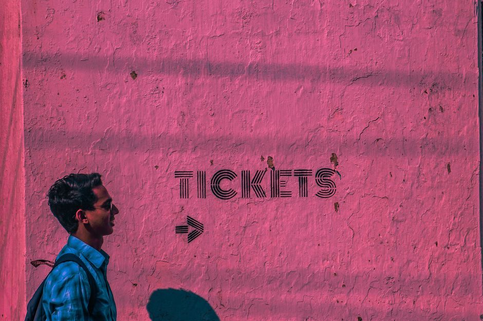 胭脂紫 — Profile view of a man walking past a textured pink wall with 'tickets' text and arrow.