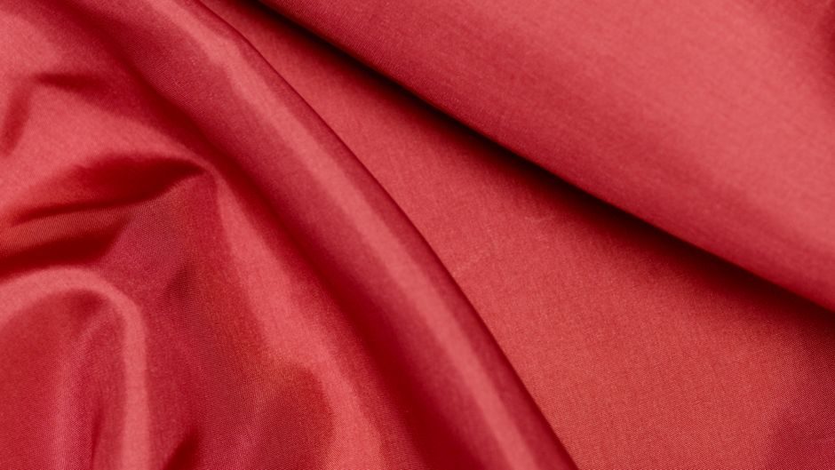 朱孔阳 — Close-up of red silk fabric showcasing soft texture and vibrant color.
